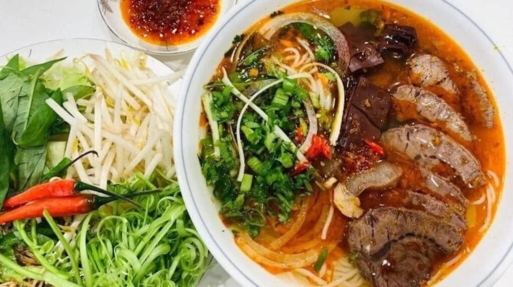 Spicy Vietnamese beef noodle soup (Bún Bò Huế) with lemongrass and chili oil, served at Ben Thanh Market in Ho Chi Minh City.