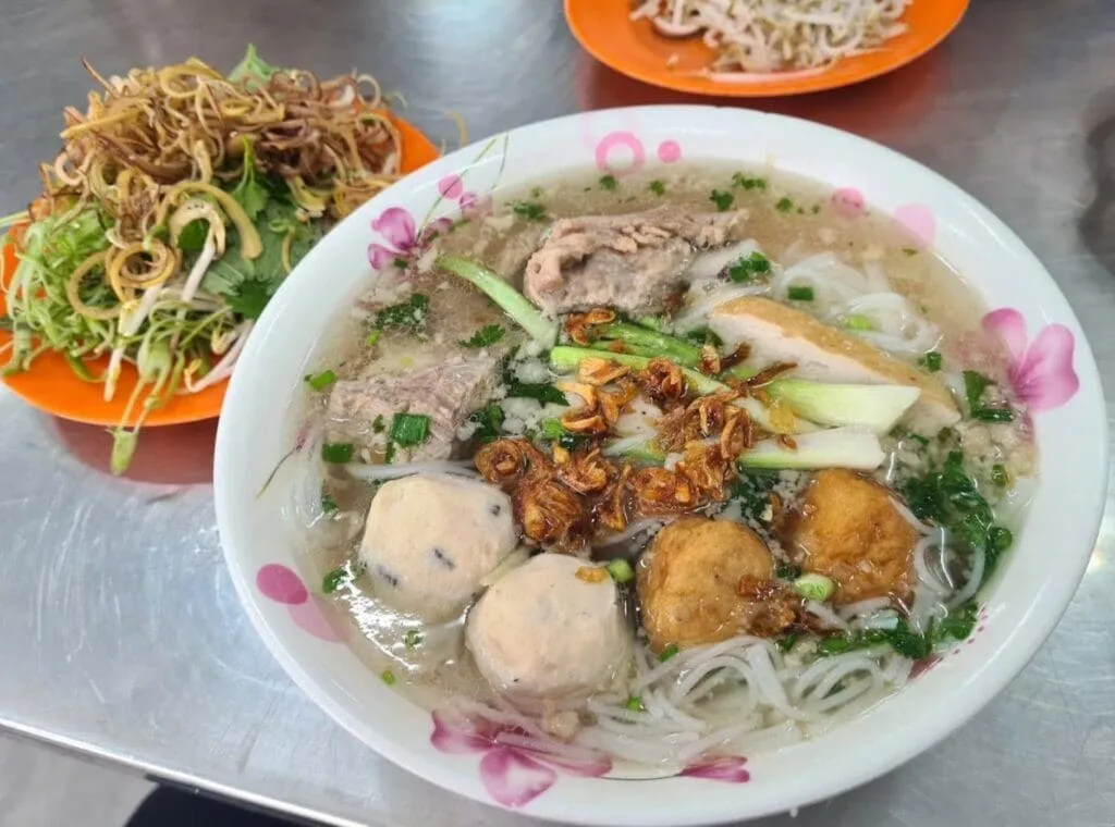 Light Vietnamese pork ball noodle soup (Bún Mọc) served with mushrooms and herbs at Ben Thanh Market in Ho Chi Minh City.
