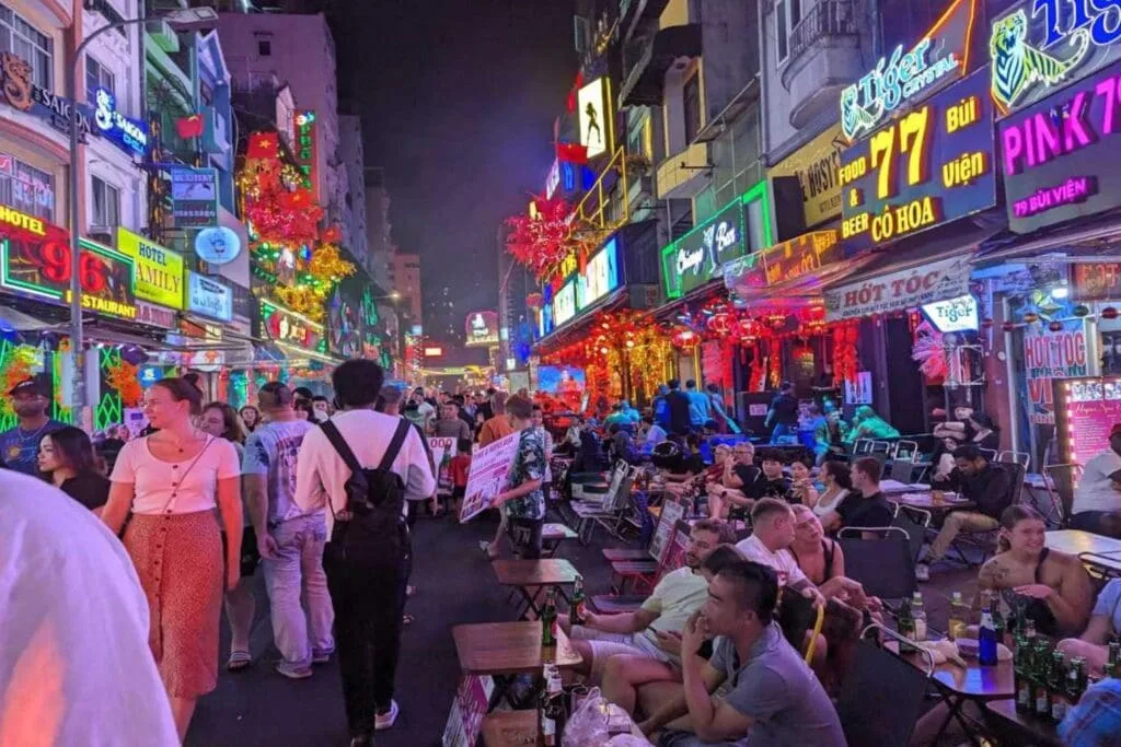Colorful nightlife on Bui Vien Street in Ho Chi Minh City with crowds of locals and tourists, lively bars, neon signs, and open-air seating.
