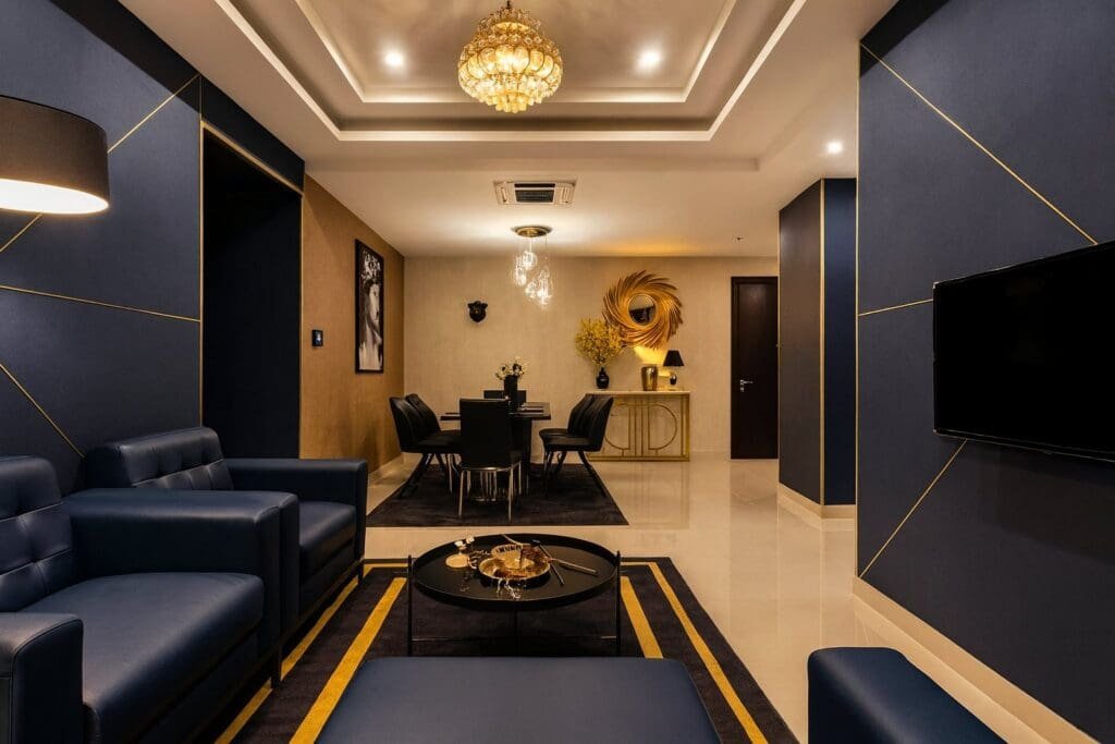 Phòng khách căn hộ 3 phòng ngủ tại RiverGate Residence, thiết kế sang trọng với sofa da, bàn ăn và đèn chùm hiện đại – lựa chọn hoàn hảo cho gia đình Việt kiều 4–6 người khi về nước nghỉ dưỡng dài ngày.
